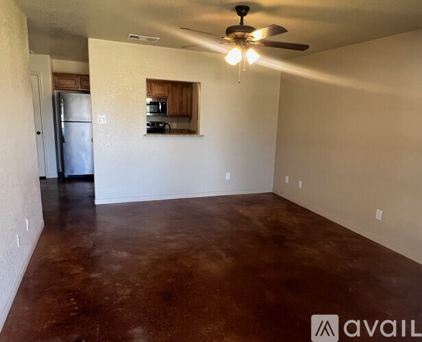 A room with a brown floor and a ceiling fan.