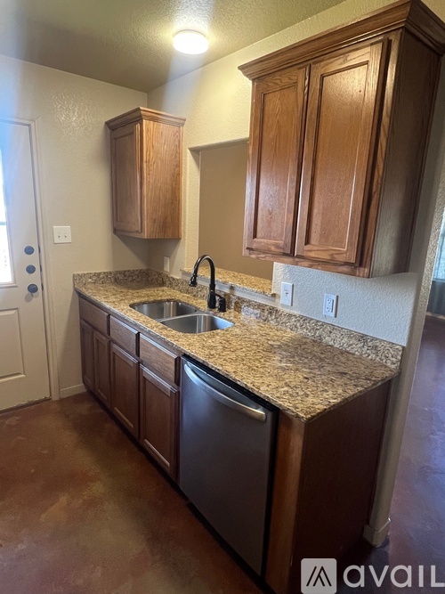 A kitchen with brown cabinets and granite countertops.