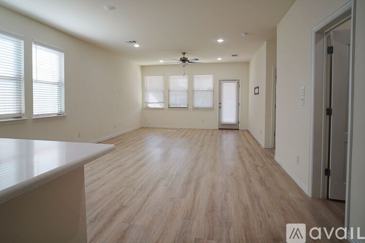 A spacious room with wooden flooring and a ceiling fan.