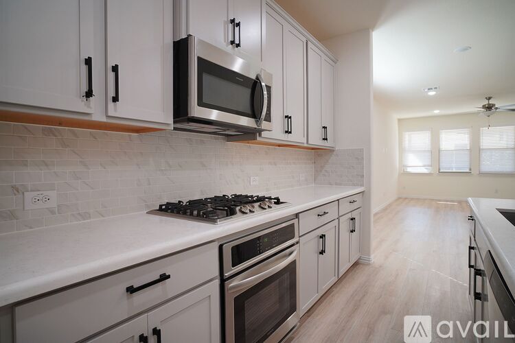 A kitchen with white cabinets and a stove top oven.