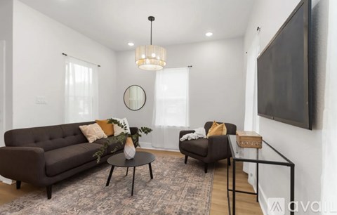 A living room with a brown sofa, a small table, and a TV mounted on the wall.