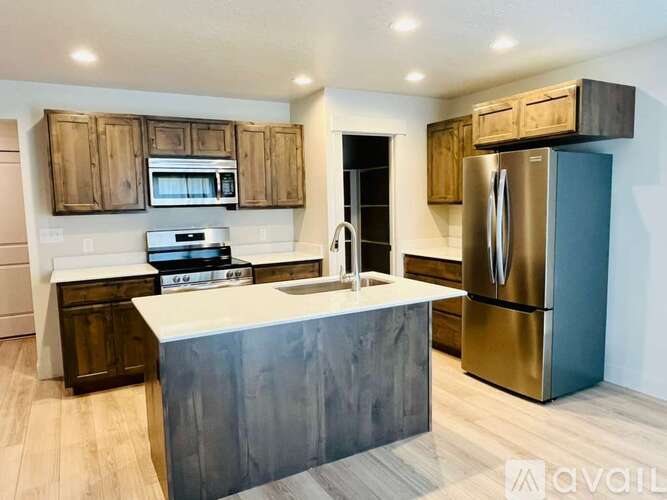 A kitchen with a white island and a stainless steel refrigerator.