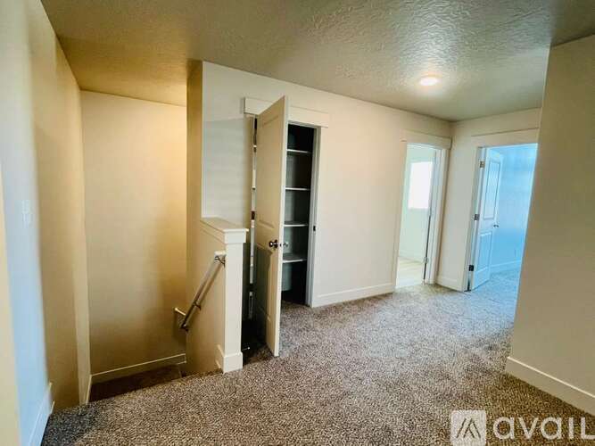 A carpeted room with a door open to another room.