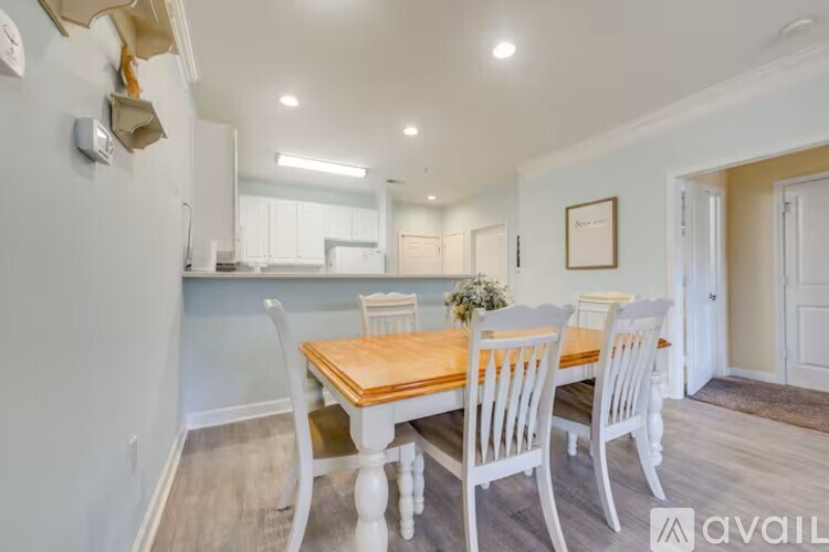A dining room with a wooden table and white chairs.