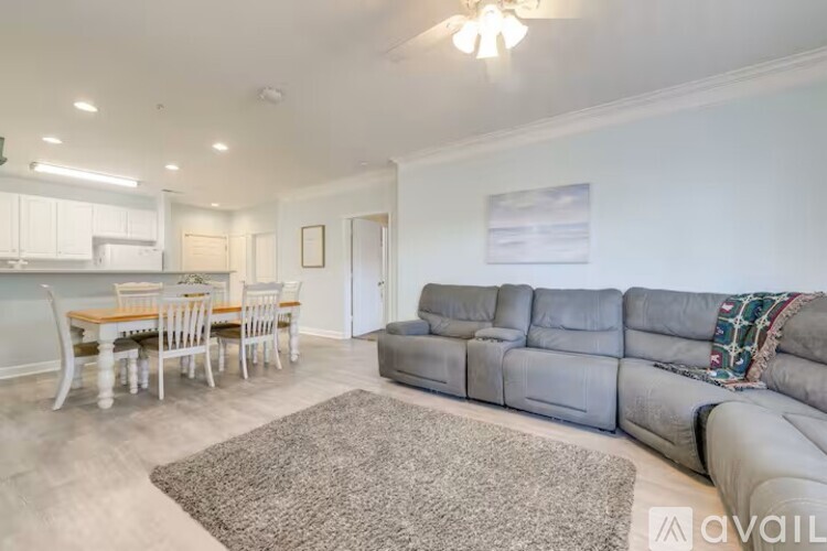 A living room with a grey sofa and a dining table with chairs.