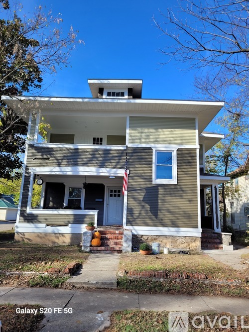 A two-story house with a flag on the front porch.