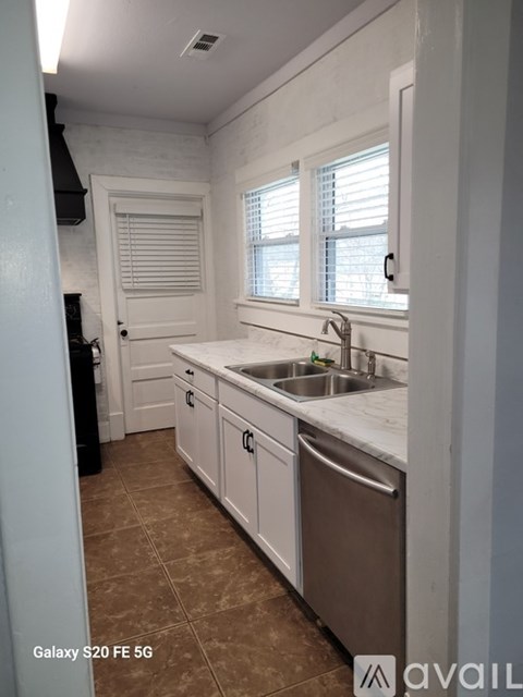 A kitchen with white cabinets and a stainless steel dishwasher.