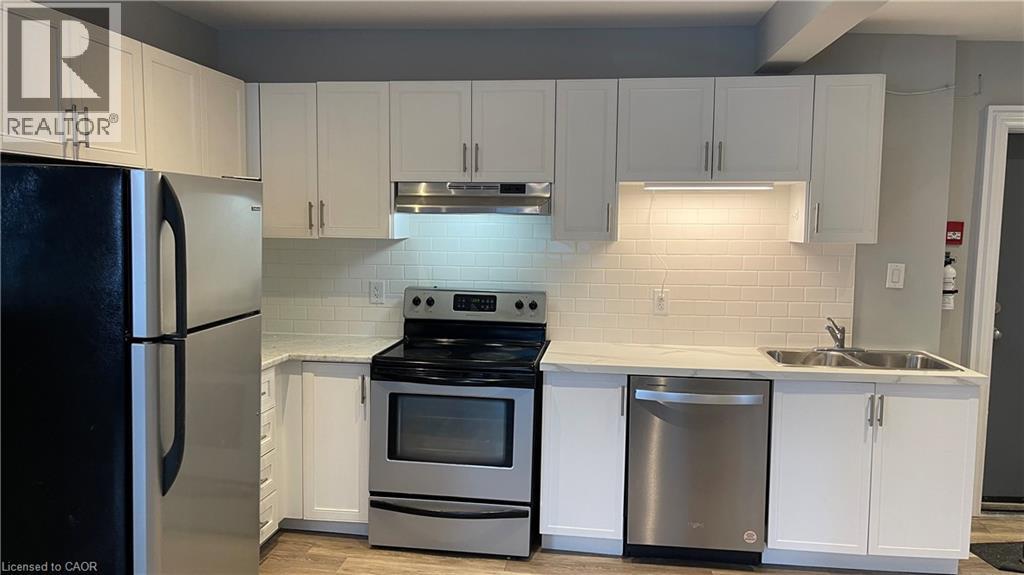 A kitchen with white cabinets and a black fridge.