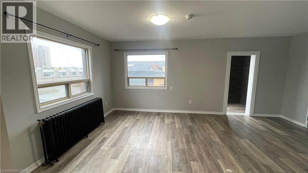 A spacious room with wood flooring and a large window.