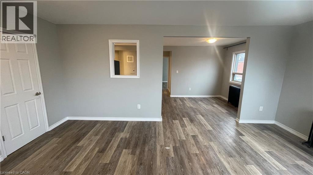 A room with wooden flooring and a door on the left.