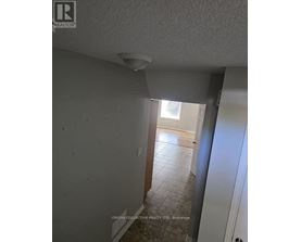 A room with a white ceiling and a doorway leading to another room.