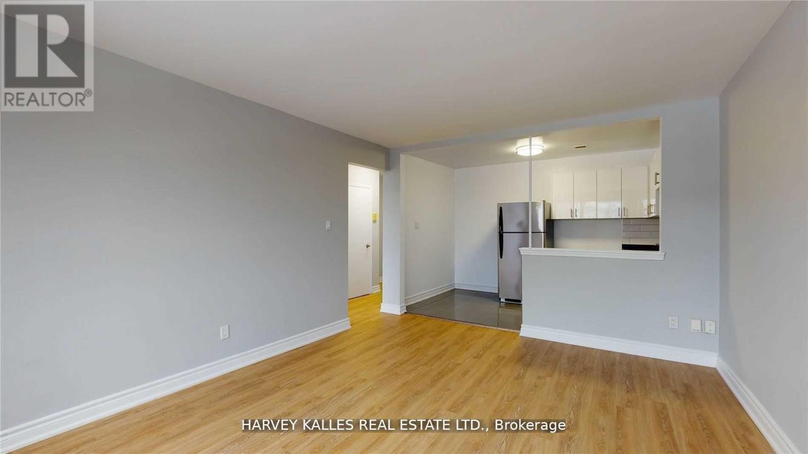 A spacious room with wooden flooring and a kitchenette in the corner.