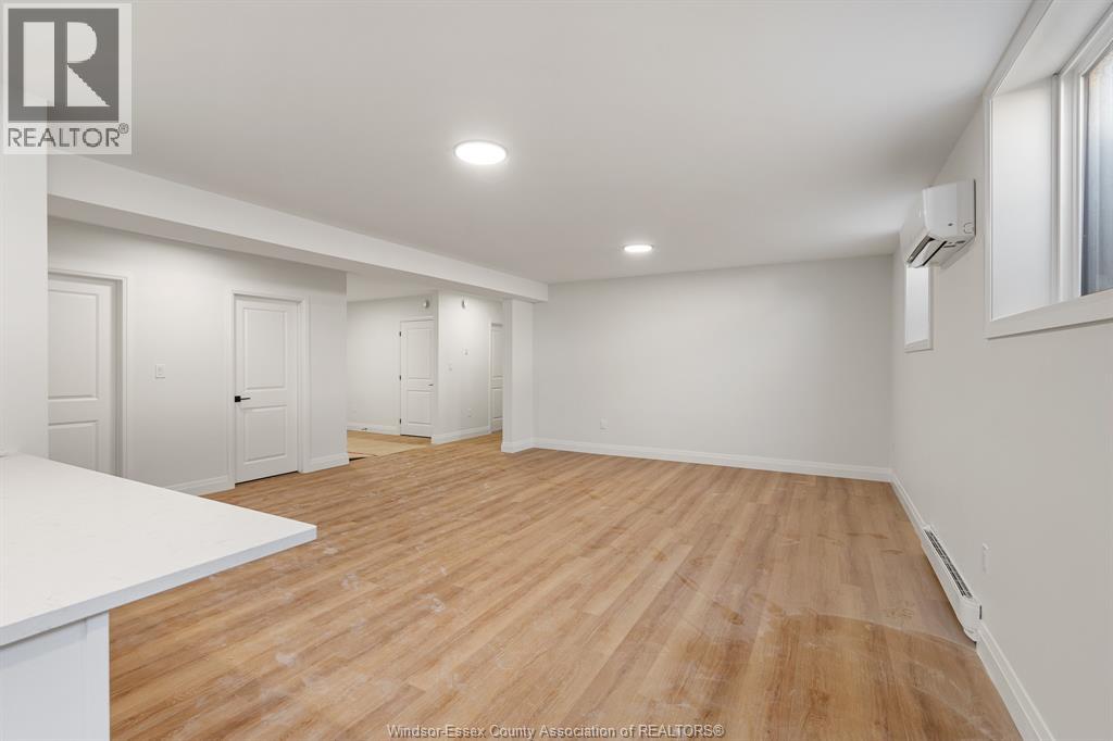 A spacious room with wooden flooring and white walls.