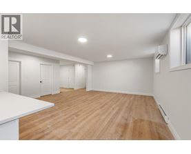 A spacious room with wooden flooring and white walls.