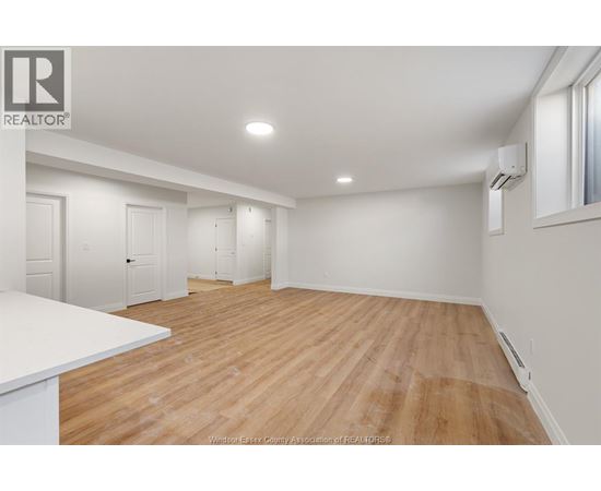 A spacious room with wooden flooring and white walls.