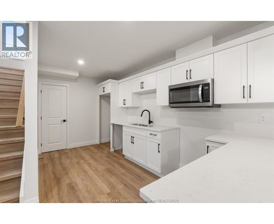 A kitchen with white cabinets and a wooden floor.