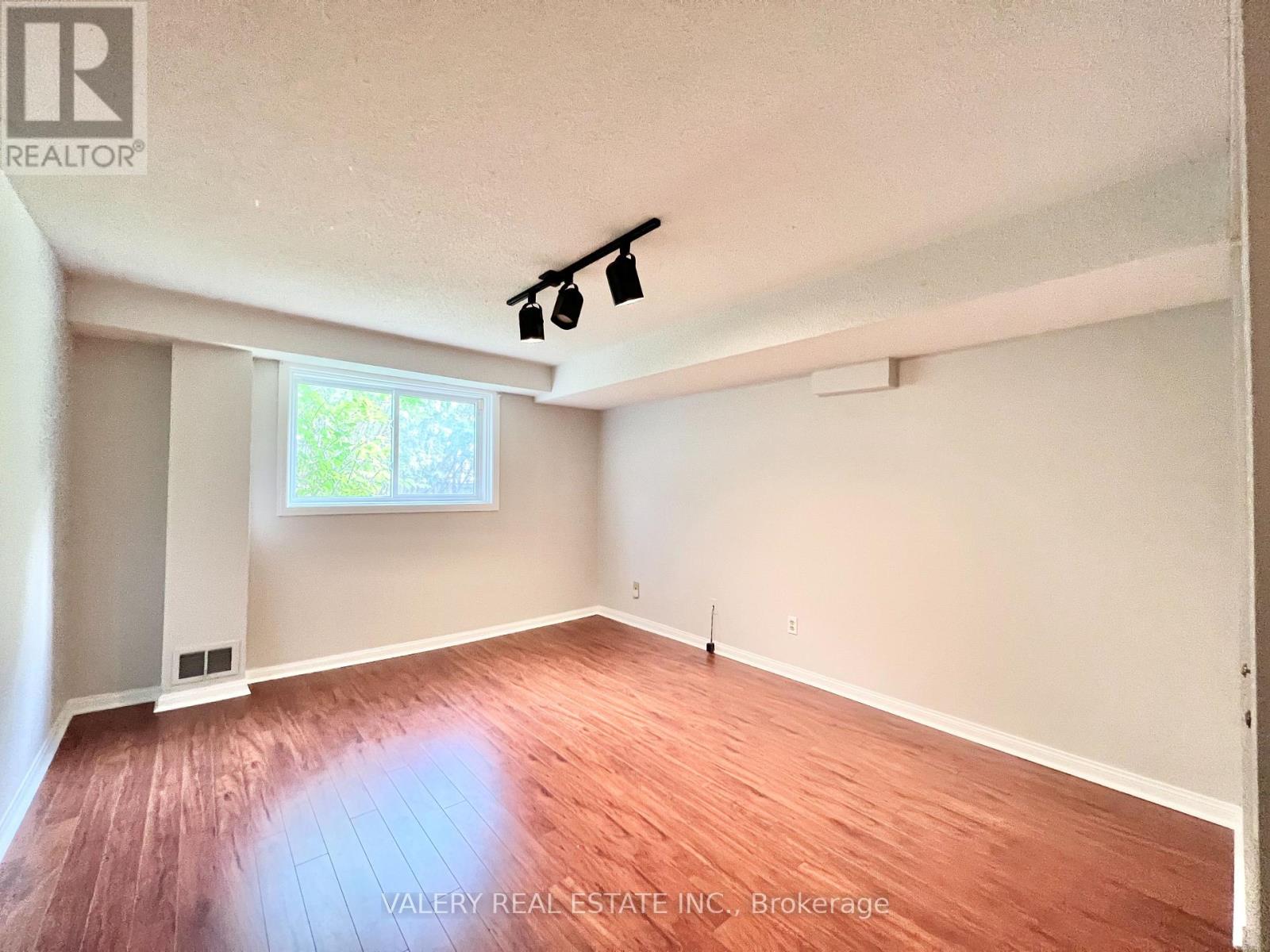A room with wooden flooring and a window letting in natural light.