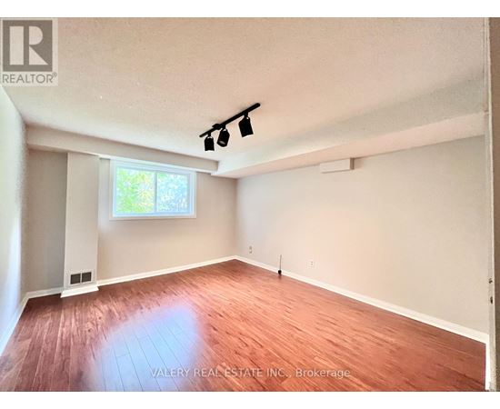 A room with wooden flooring and a window letting in natural light.