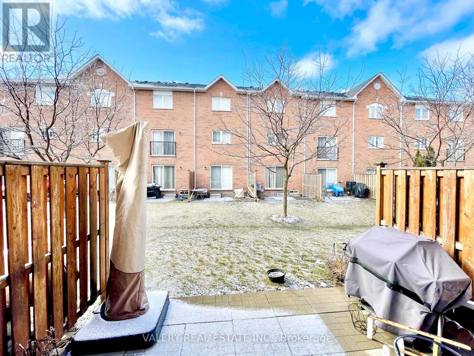 A view of a courtyard with a building in the background and a patio with a chair and umbrella in the foreground.