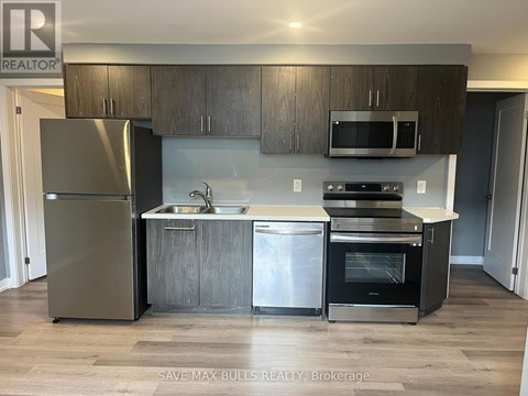 A kitchen with a refrigerator, sink, oven and microwave.