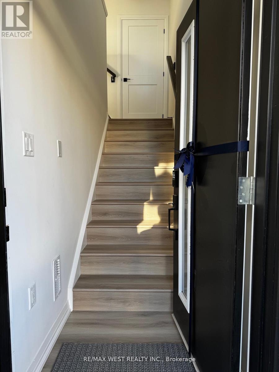 A hallway with a wooden staircase and a black door.