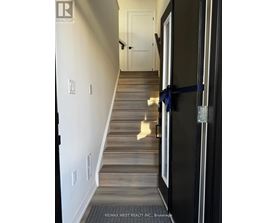 A hallway with a wooden staircase and a black door.