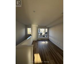 A spacious room with wooden floors and a large window.