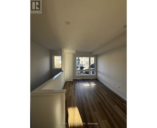 A spacious room with wooden floors and a large window.