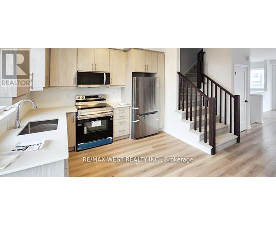 A kitchen with a refrigerator, microwave, oven and sink.