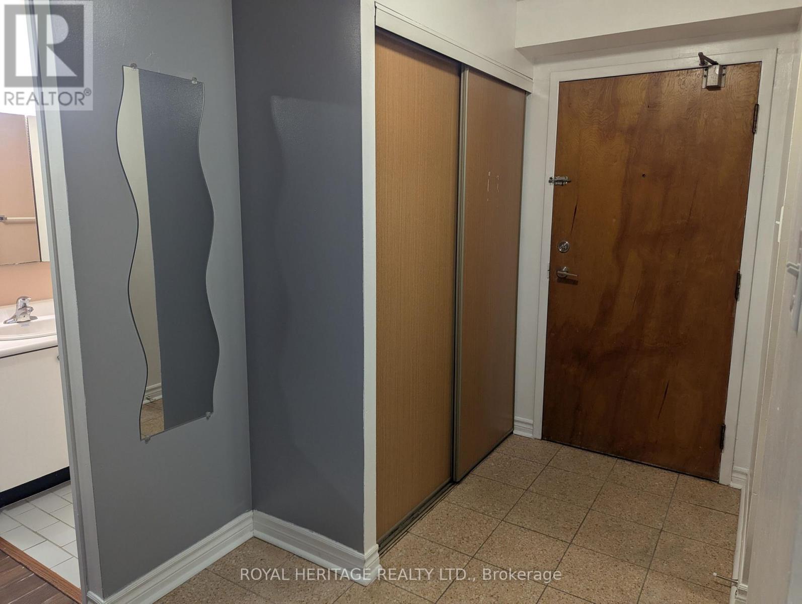 A hallway with a wooden door and a grey wall.