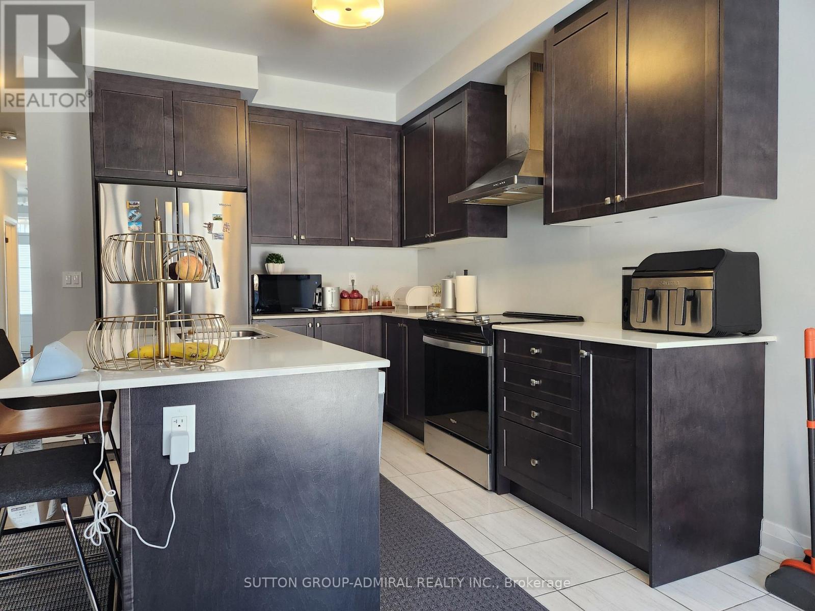 A kitchen with dark brown cabinets and a black fridge.