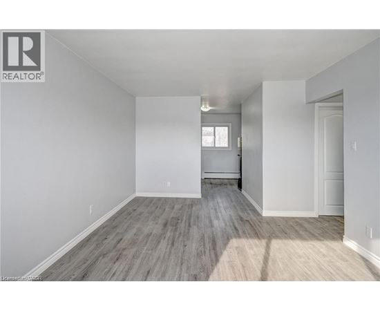 A spacious room with wooden flooring and white walls.