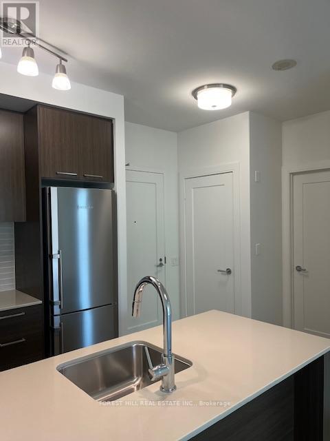 A modern kitchen with a stainless steel refrigerator and a sink with a chrome faucet.