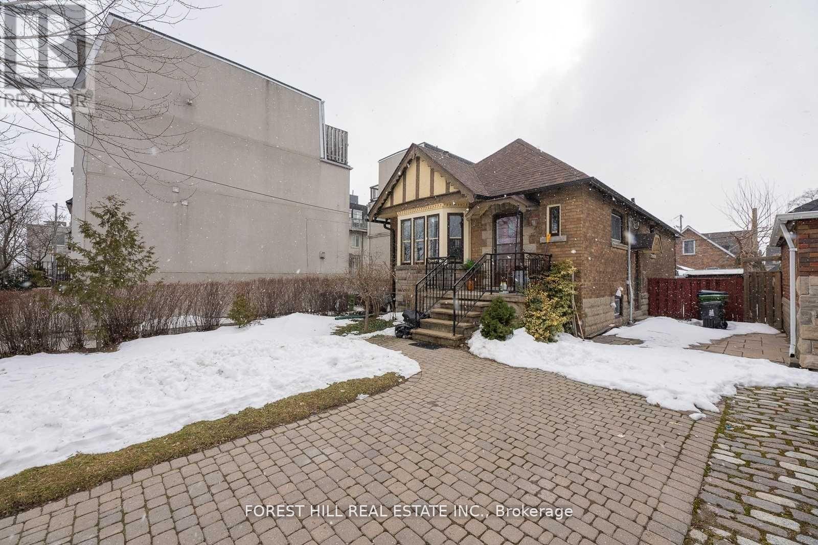 A brick house with a snow-covered front yard.