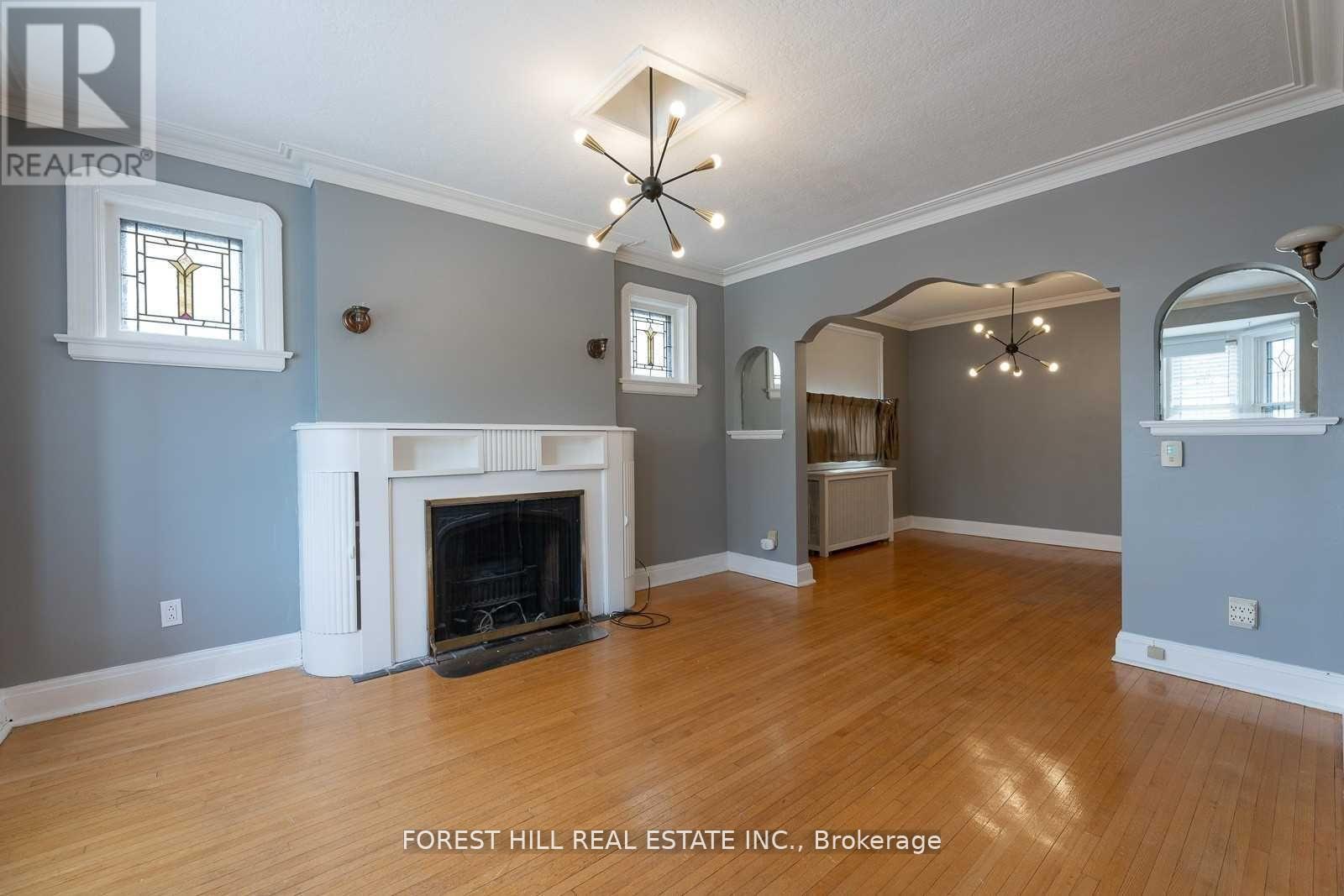 A large, empty room with a fireplace and wooden floors.