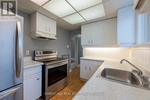 A kitchen with white cabinets and a stainless steel refrigerator.