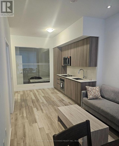 A living room with a grey couch and a wooden floor.