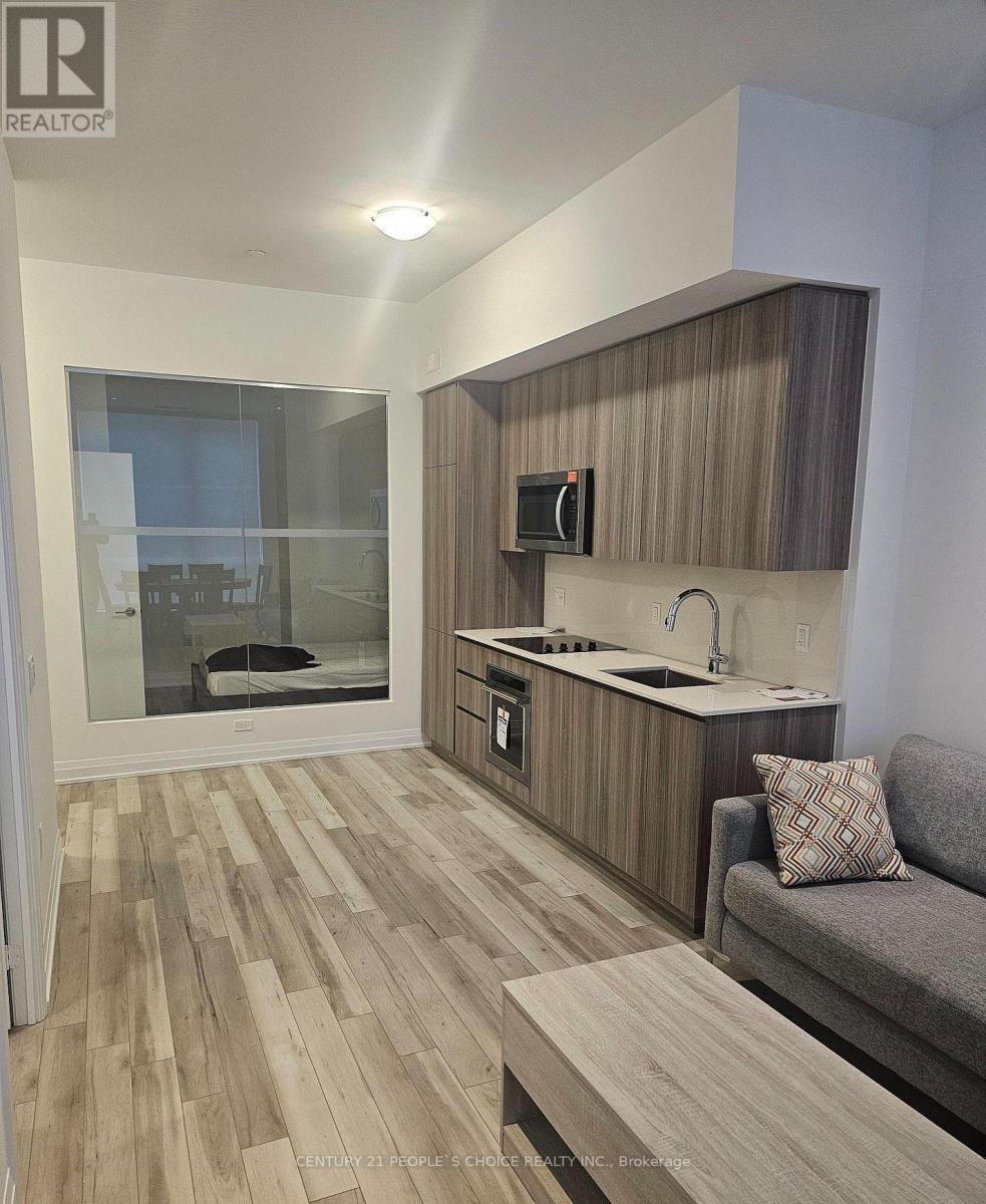 A modern kitchen with wooden floors and a grey sofa.