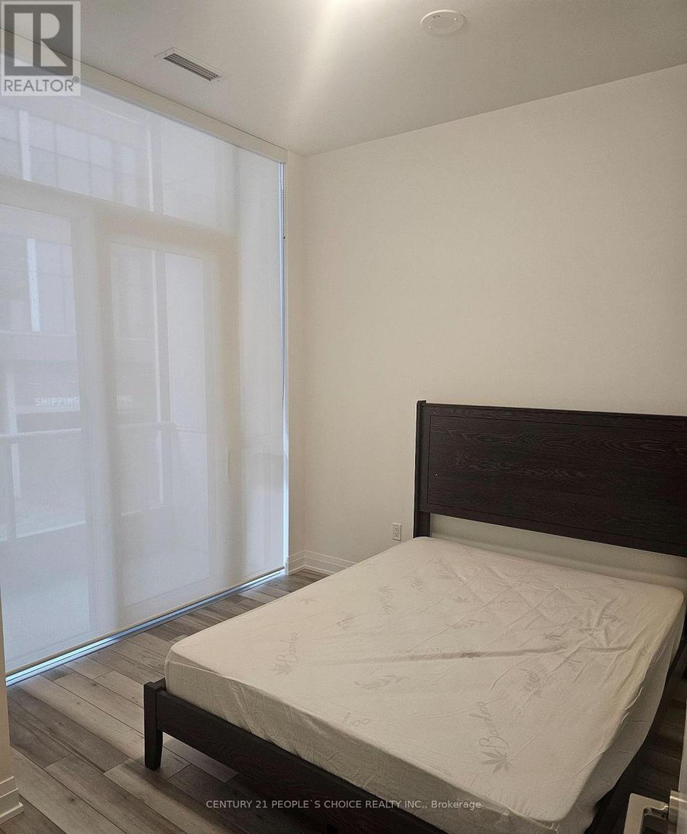A bedroom with a bed, wooden headboard, and a window with white blinds.