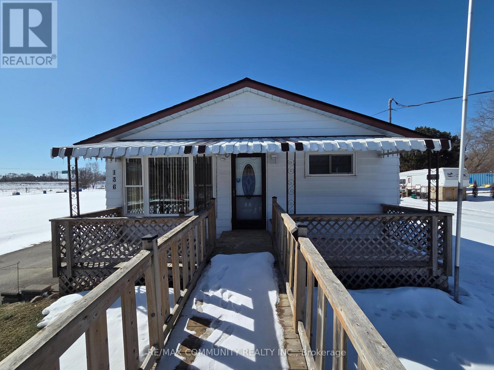 A house with a porch and a fence in front of it.