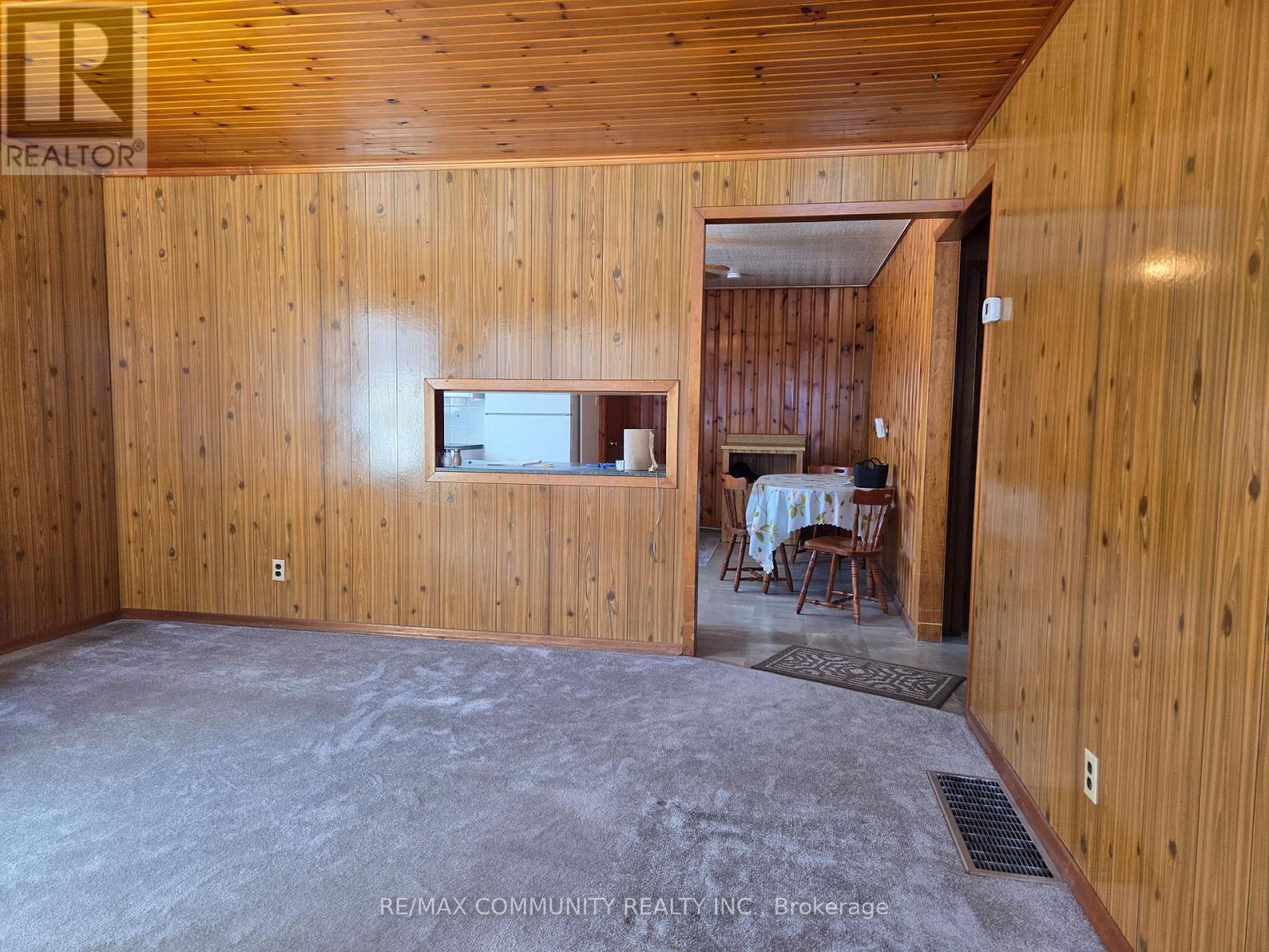 A room with wooden walls and a dining area in the background.