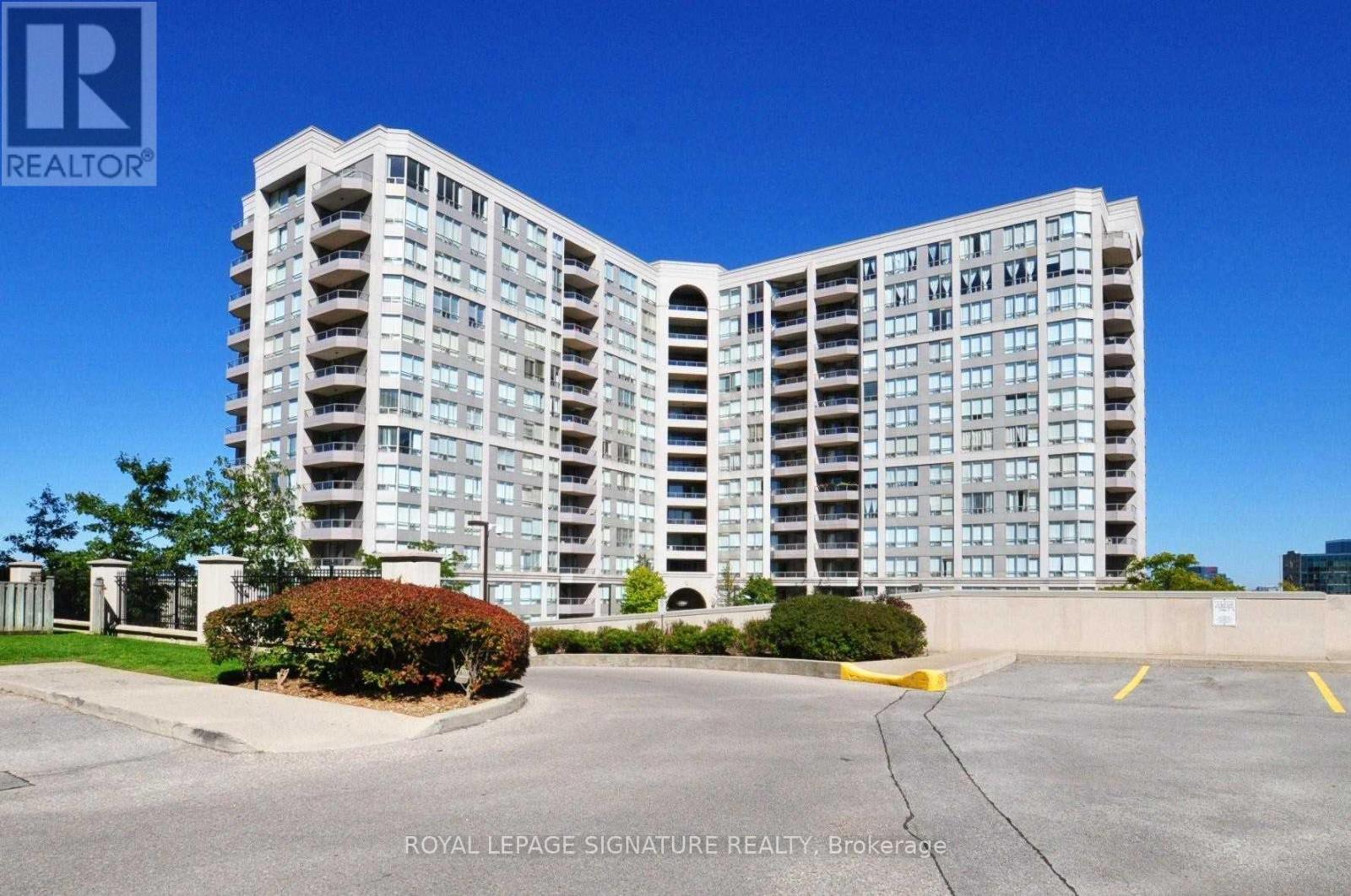A large, modern apartment building with a parking lot in front.