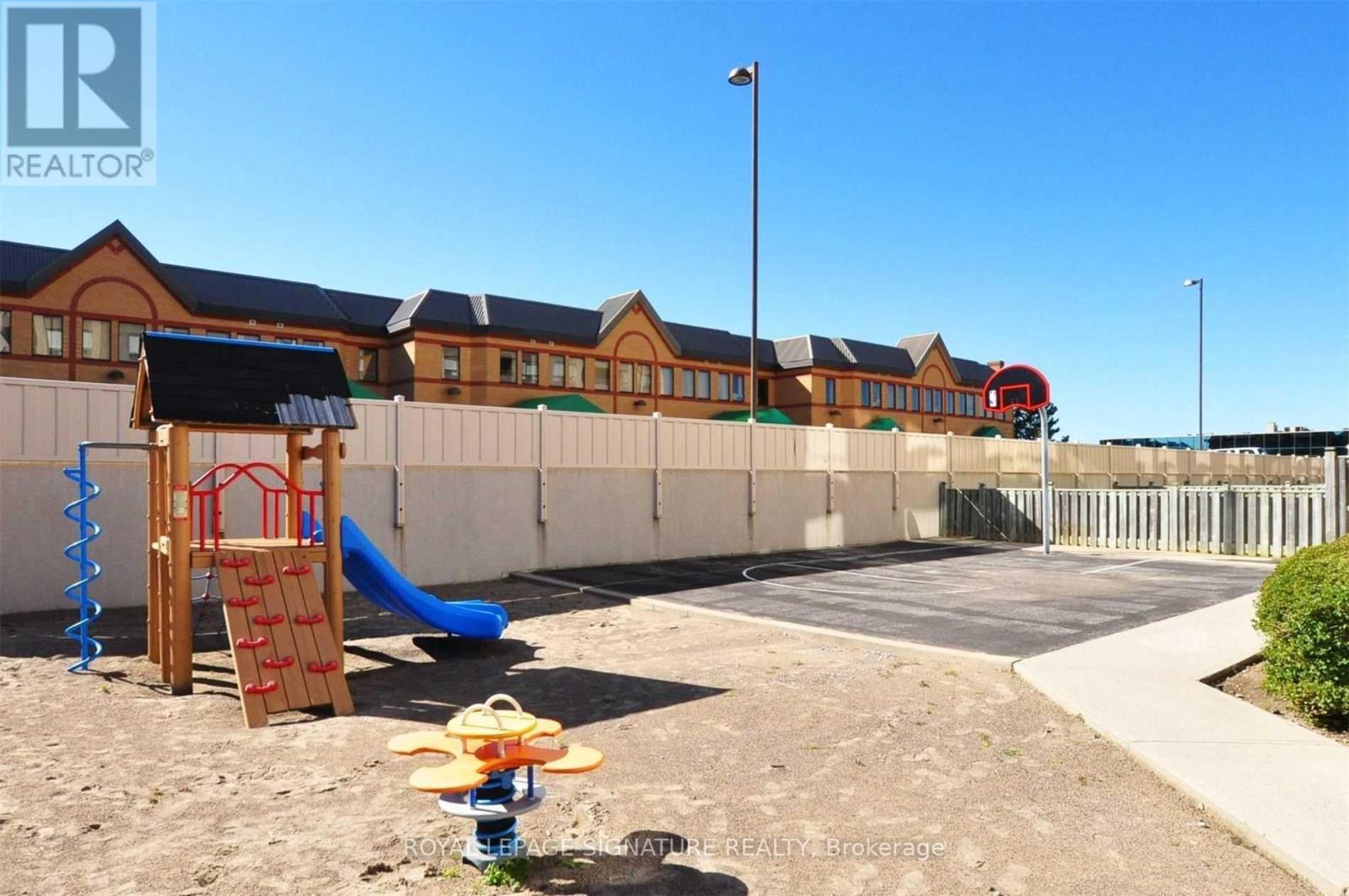 A playground area with a slide and sandbox in front of a building.