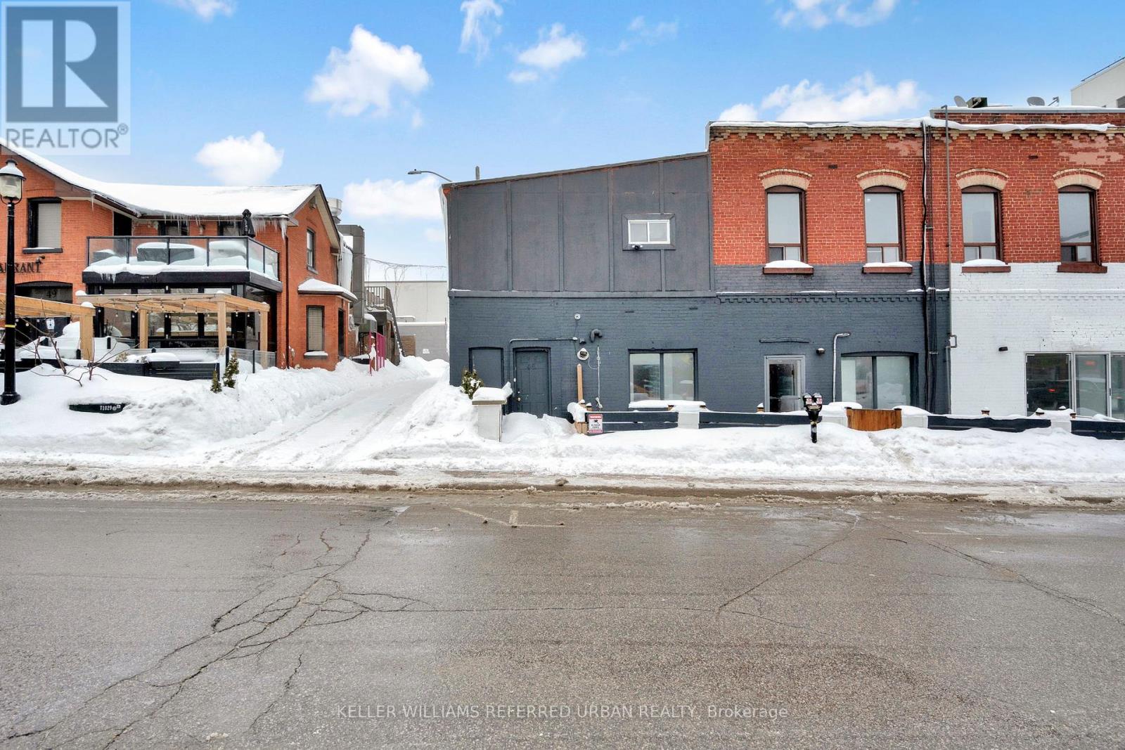 A street view with buildings and a person standing on the sidewalk.