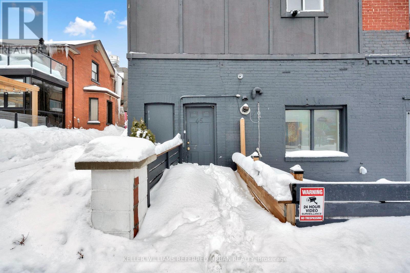 A snow-covered street with a warning sign in front of a grey building.