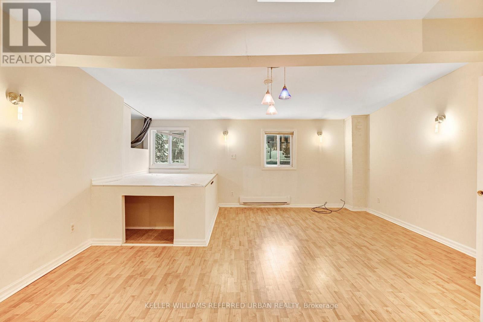 A spacious room with a fireplace and wood flooring.