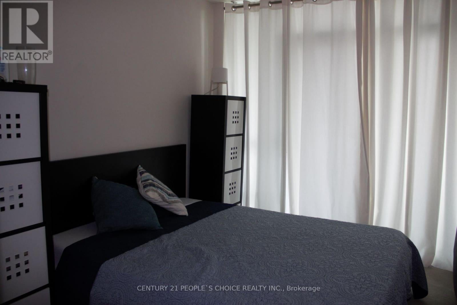 A bedroom with a bed, nightstand, and a wall-mounted cabinet.