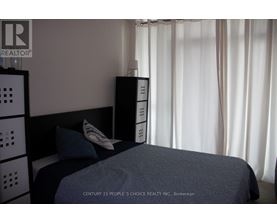 A bedroom with a bed, nightstand, and a wall-mounted cabinet.