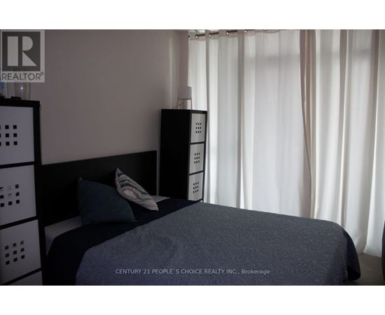 A bedroom with a bed, nightstand, and a wall-mounted cabinet.