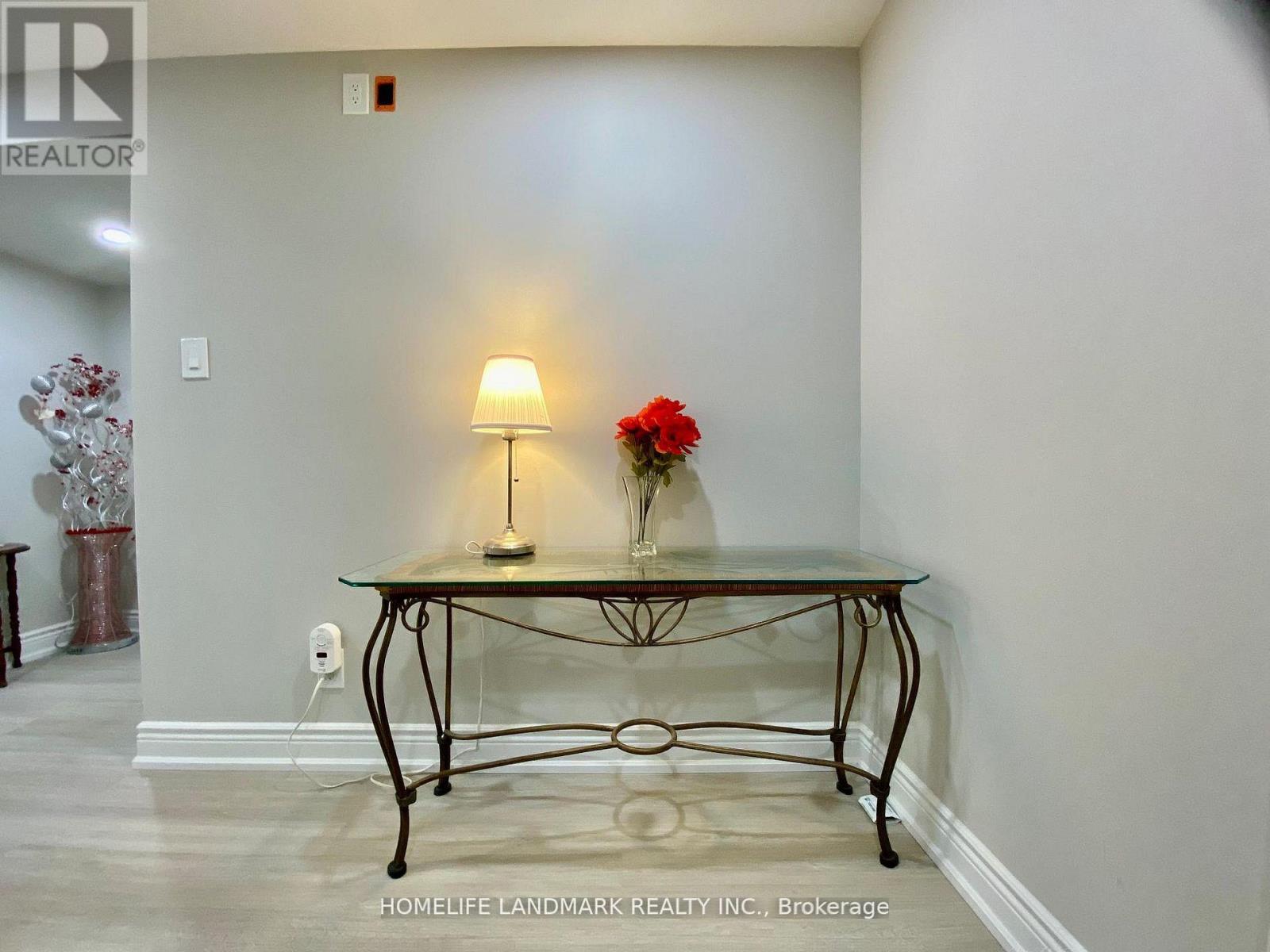 A glass table with a flower and a lamp on it.